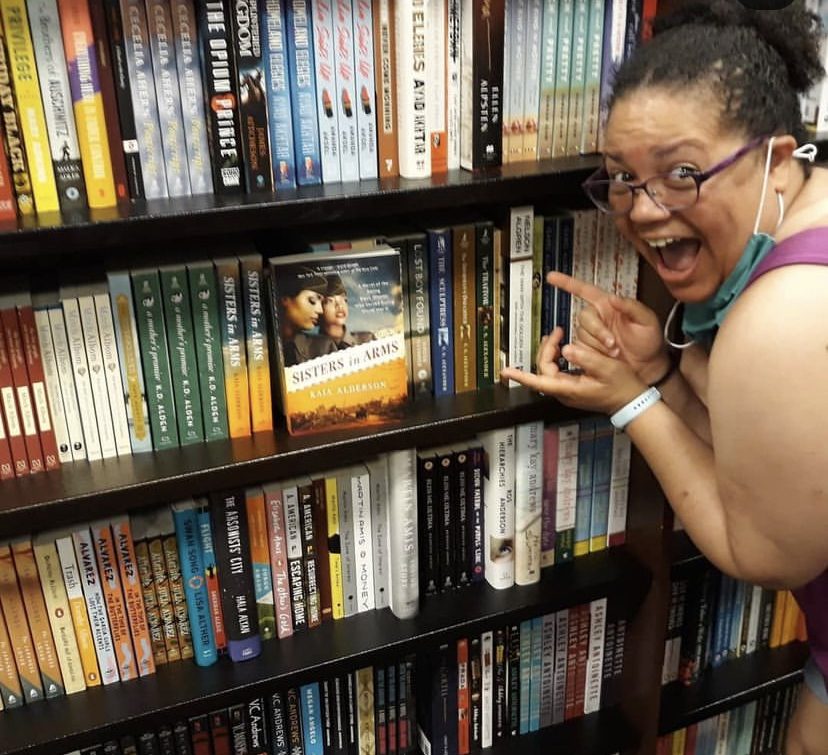 Author Kaia posing with her books in a bookstore