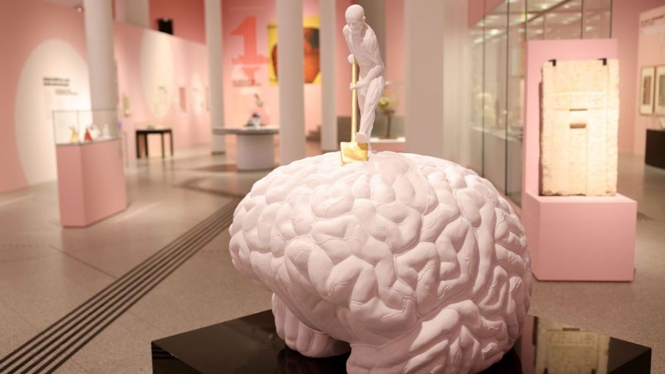 A man with a golden shovel on top of a large white brain marble sculpure by Jan Fabre, 'Anthropology of a Planet' is pictured during the The Brain exhibition at Bundeskunsthalle on January 31, 2022 in Bonn, Germany. (Photo by Andreas Rentz/Getty Images)