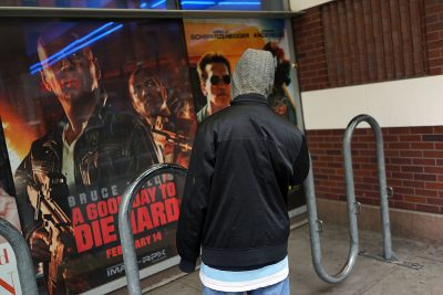 A teen stands in front of posters advertising new action films at a Brooklyn movie theater on January 11, 2013 in New York City.  (Photo by Spencer Platt/Getty Images)