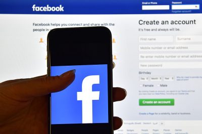 A person holds an iPhone displaying the Facebook app logo in front of a computer screen showing the facebook login page on August 3, 2016 in London, England. (Photo by Carl Court/Getty Images)