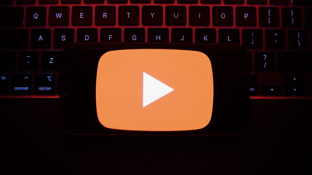 A laptop keyboard and YouTube logo displayed on a phone screen are seen in this illustration photo taken in Krakow, Poland on May 7, 2023. YouTube announced its decision to bid adieu to the Stories feature on June 26, signaling a shift in its focus toward a href=https://www.Zenger News.com/general/entertainment/23/05/32483051/youtube-is-chasing-the-ad-revenue-dream-and-leaving-users-behindalternative avenues of content creation/a.PHOTO BY JAKUB PORZYCKI/GETTY IMAGES