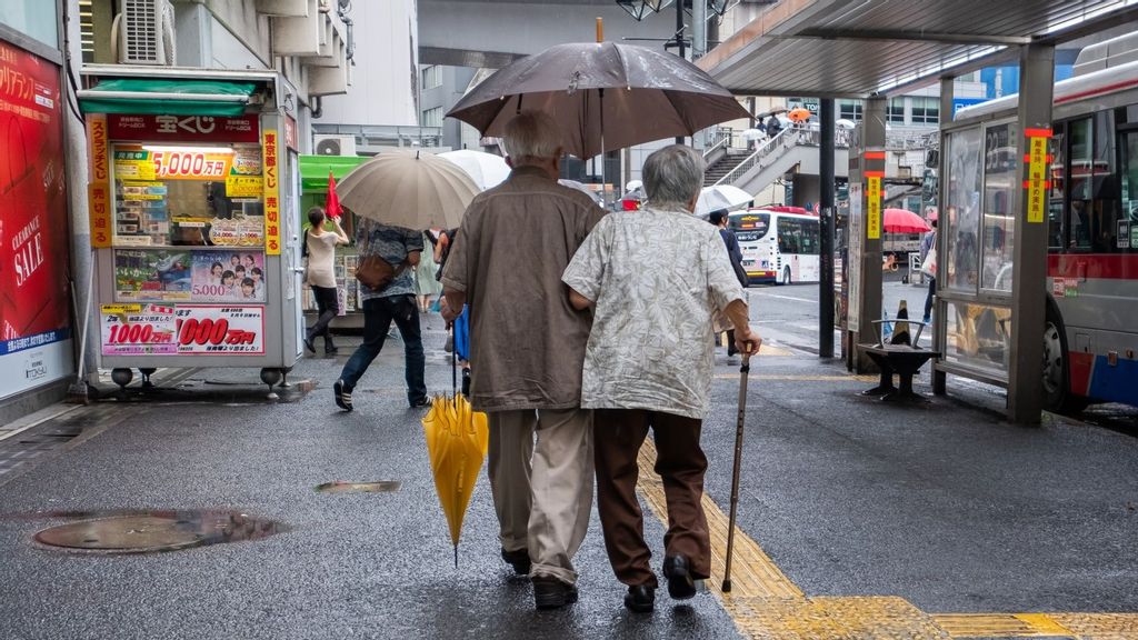 Old Japanese couple walking at a bus stop with umbrella during a rainy day, Shibuya, Tokyo on July 4th, 2018. SHUTTERSTOCK