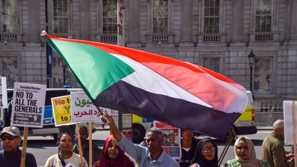 A protester waves a Sudanese flag during a demonstration. International media analyst Mekki Elmograbi said that regarding the war in Israel, Sudan is content to support mediation efforts to calm the situation. VUK VALCIC/SOPA IMAGES/LIGHT ROCKET VIA GETTY IMAGES.