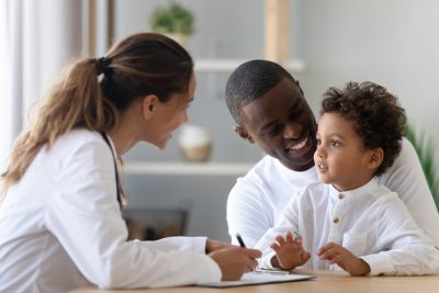 Cheerful,Young,Female,Pediatrician,And,African,American,Smiling,Father,Listening