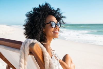 Happy,Young,Black,Woman,Relaxing,On,Deck,Chair,At,Beach