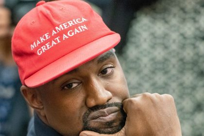 Kanye West wearing a Black shirt and red MAGA hat.