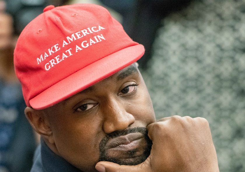 Kanye West wearing a Black shirt and red MAGA hat.