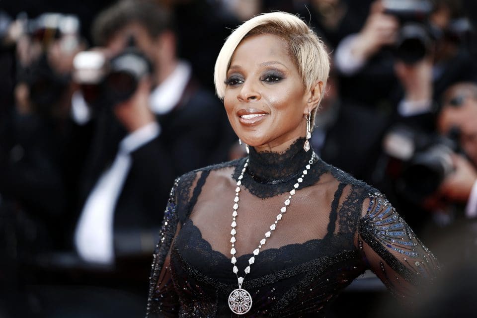 Mary J. Blige wears a black dress on the red carpet.