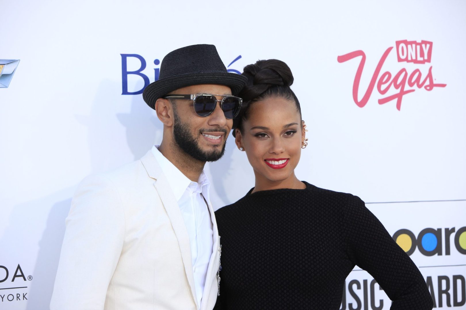 Celebrity couple, Swizz Beatz dressed in a white suit with wife Alicia Keys donning a black dress on the red carpet.