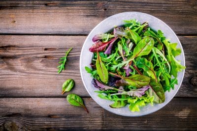 Fresh salad with mixed greens in bowl on wooden background images