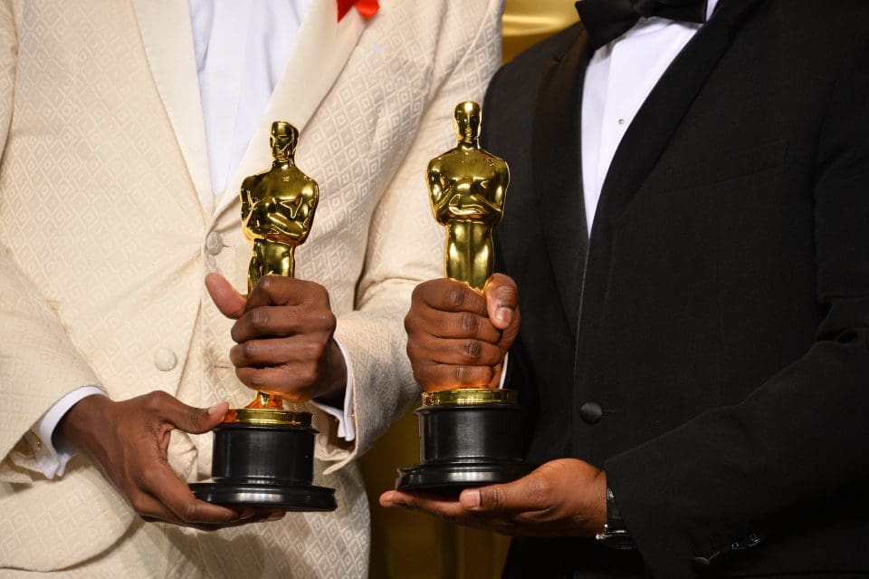 Two men of color hold the Oscars they won .