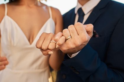 couple locking fingers with wedding bands