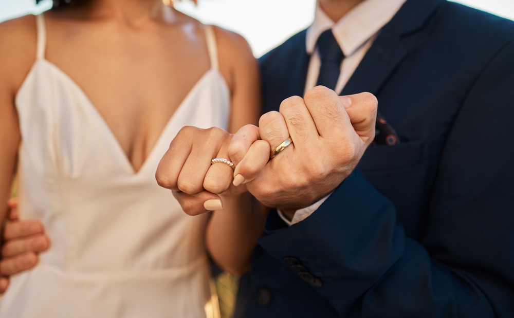 couple locking fingers with wedding bands