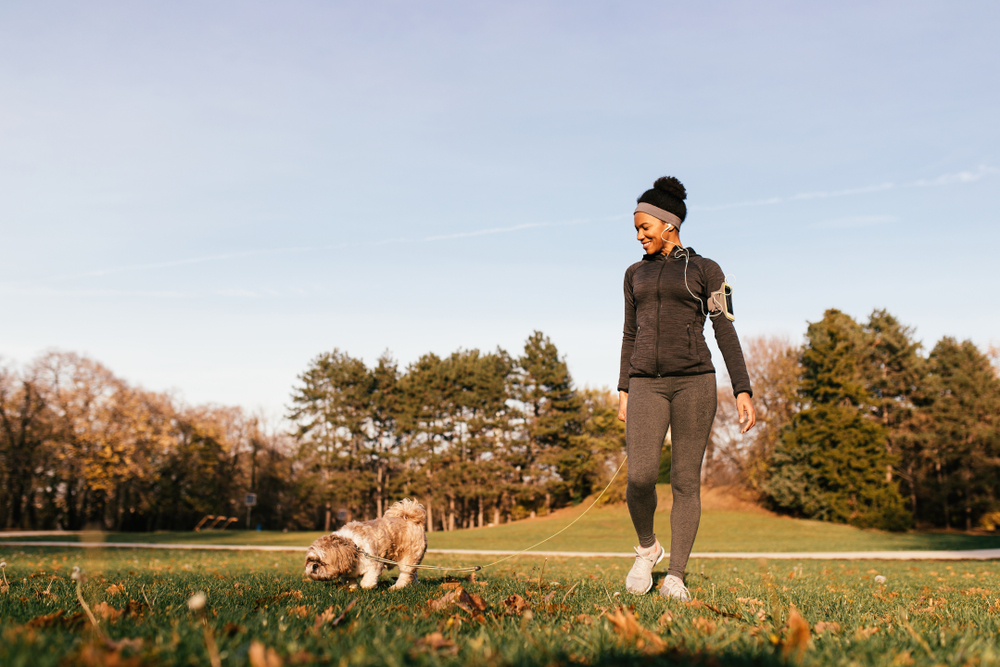 An African American woman walking with her dog