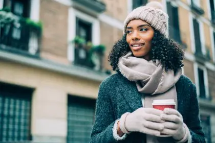 African American woman wearing a winter coat and holding a cup of coffee