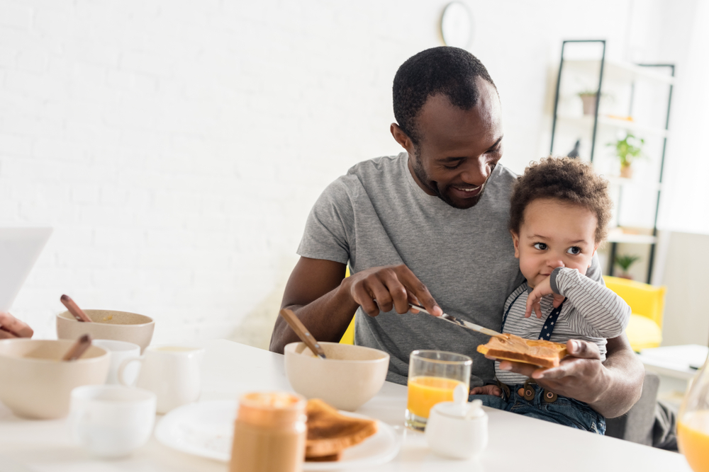 Father applying peanut butter on toast