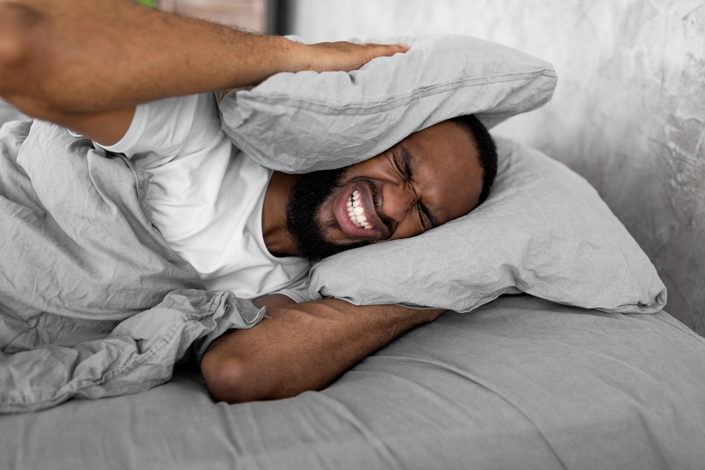 African American man unable to sleep due to loud sounds